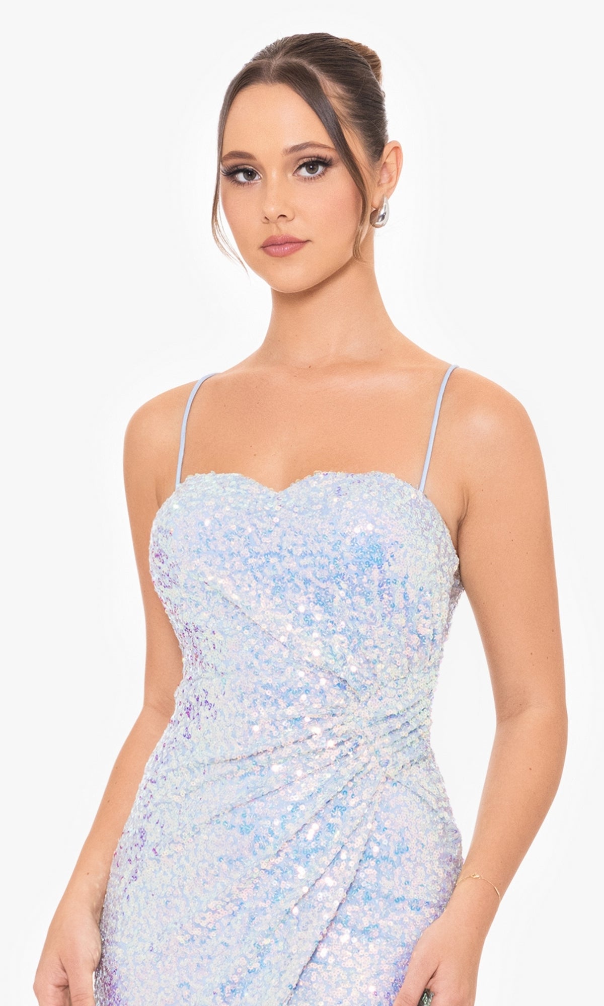 A woman wears the Blondie Nites Long Sequin Prom Dress 4727BN with thin straps, featuring iridescent sequins, as she stands against a plain white background and looks at the camera.